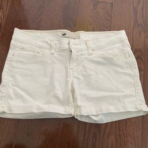 White Jean shorts with peach colored stitching. Levi shorts
